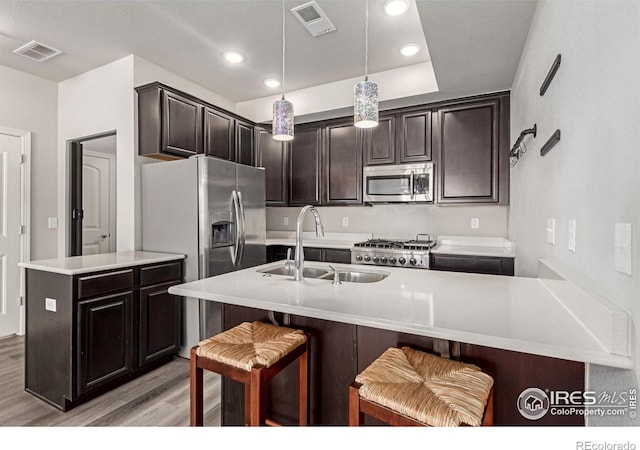 kitchen with a kitchen island with sink, appliances with stainless steel finishes, light countertops, and a sink