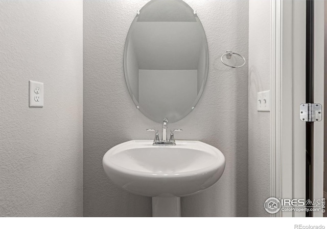 bathroom featuring a textured wall and a sink