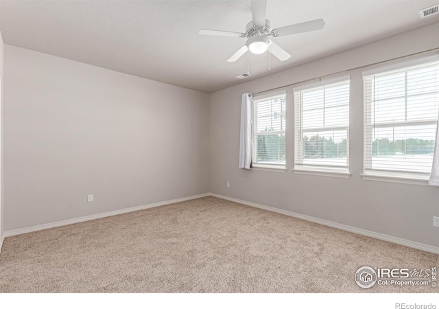 spare room featuring ceiling fan, visible vents, baseboards, and light colored carpet