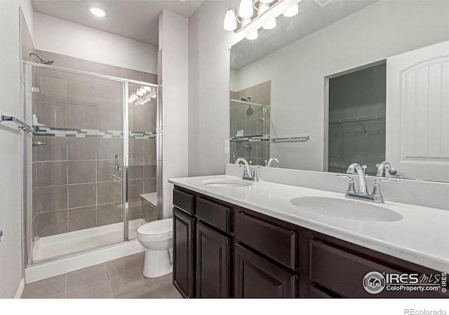 bathroom with a sink, a shower stall, toilet, and tile patterned floors