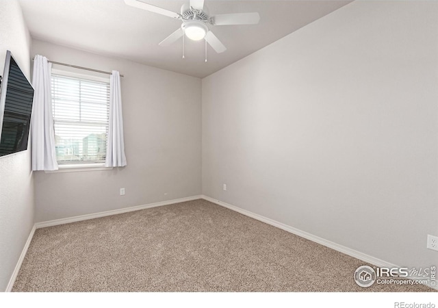 carpeted spare room with ceiling fan and baseboards