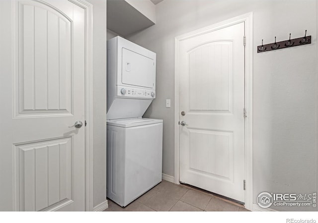 clothes washing area featuring stacked washer / drying machine and light tile patterned flooring