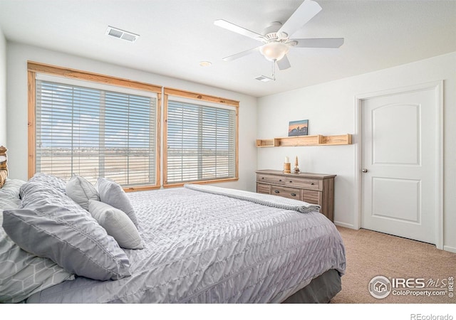 bedroom with light carpet, visible vents, and a ceiling fan