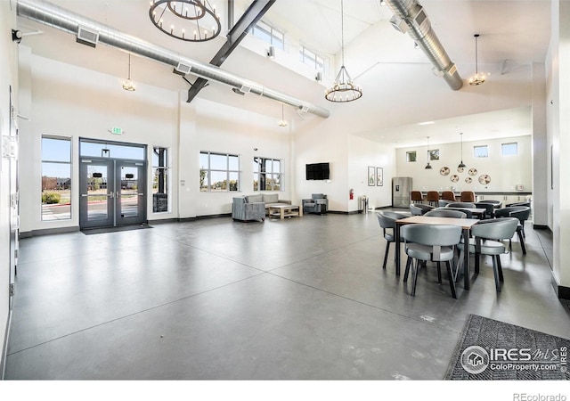 interior space with french doors, visible vents, a high ceiling, concrete flooring, and baseboards