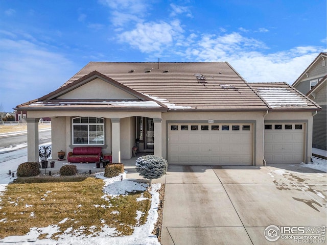 view of front of home with covered porch, a tiled roof, stucco siding, and a garage