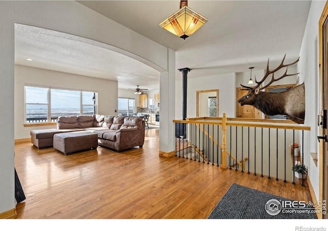 interior space with arched walkways, a textured ceiling, baseboards, and wood finished floors