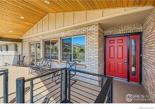 view of exterior entry featuring board and batten siding, brick siding, and a porch