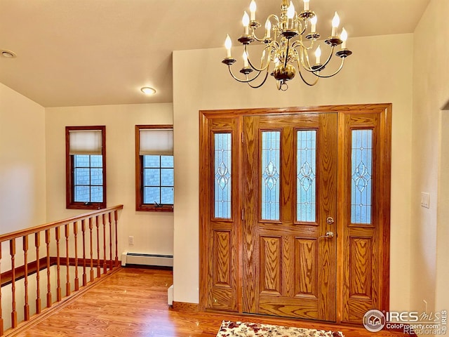 foyer entrance featuring a chandelier, baseboard heating, and wood finished floors