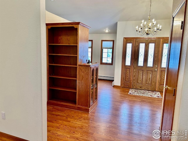 foyer entrance featuring a baseboard radiator, a notable chandelier, and wood finished floors