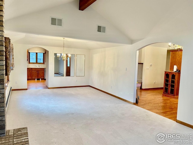 carpeted spare room with an inviting chandelier, visible vents, arched walkways, and high vaulted ceiling