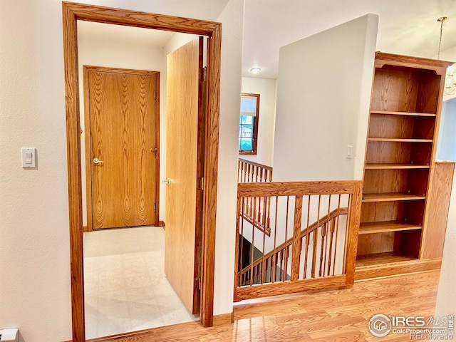 corridor featuring wood finished floors and an upstairs landing