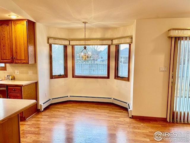 unfurnished dining area with a baseboard heating unit, a wealth of natural light, baseboards, and light wood finished floors