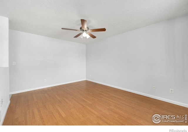 unfurnished room with a textured ceiling, wood finished floors, a ceiling fan, and baseboards