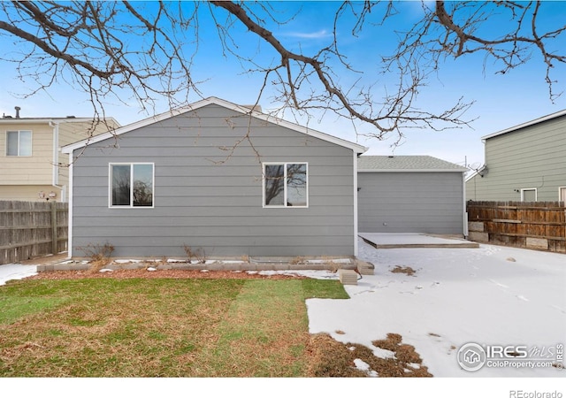 rear view of property featuring a yard and fence