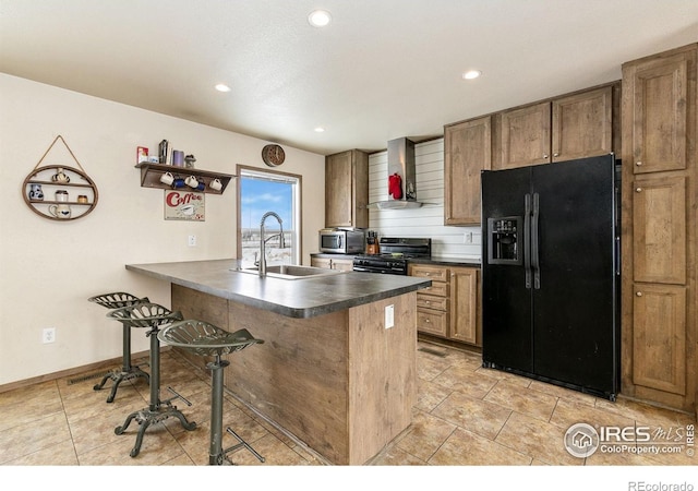 kitchen with brown cabinets, dark countertops, a sink, wall chimney range hood, and black appliances