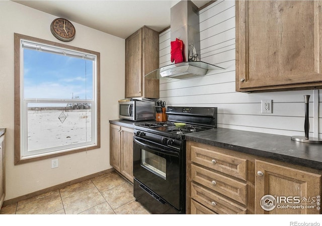 kitchen with black gas range oven, dark countertops, wall chimney exhaust hood, stainless steel microwave, and brown cabinets