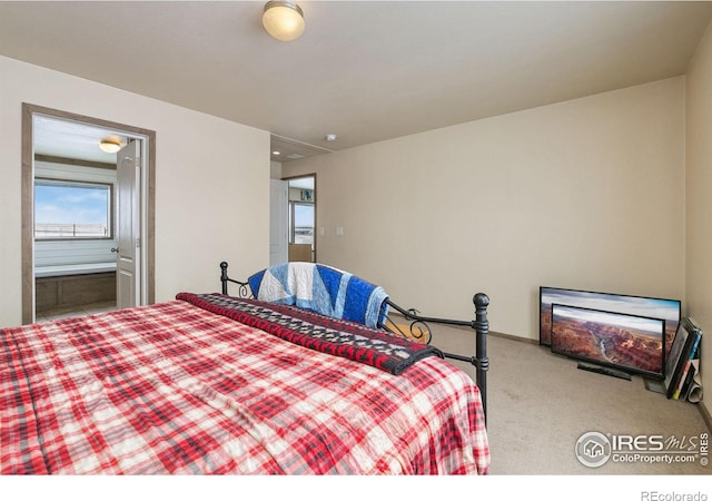 carpeted bedroom featuring connected bathroom and baseboards