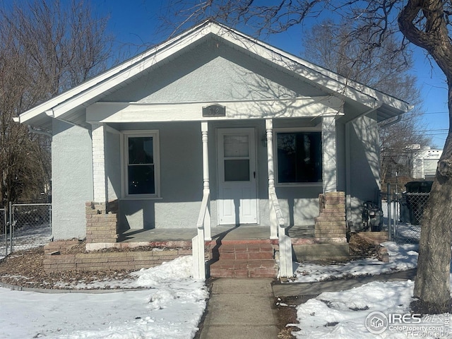 bungalow featuring fence and stucco siding