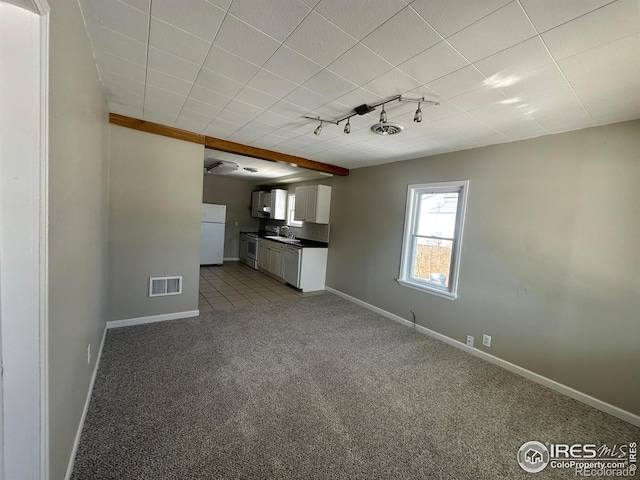 interior space featuring a sink, carpet flooring, visible vents, baseboards, and track lighting