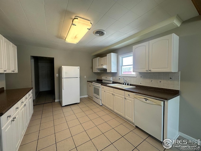 kitchen featuring white appliances, dark countertops, a sink, and white cabinets