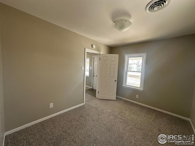 empty room featuring baseboards, visible vents, and carpet flooring