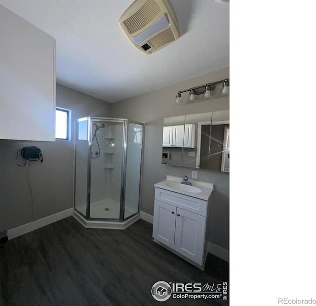 full bathroom featuring a stall shower, visible vents, baseboards, wood finished floors, and vanity