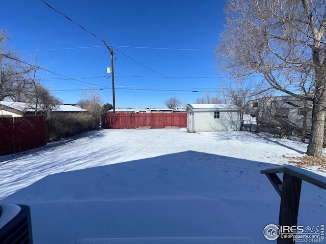 yard layered in snow with a storage shed, an outdoor structure, and fence