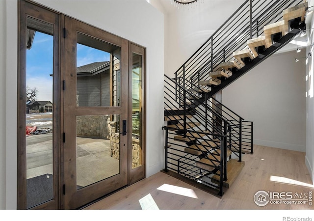 doorway to outside featuring light wood-type flooring, baseboards, and french doors