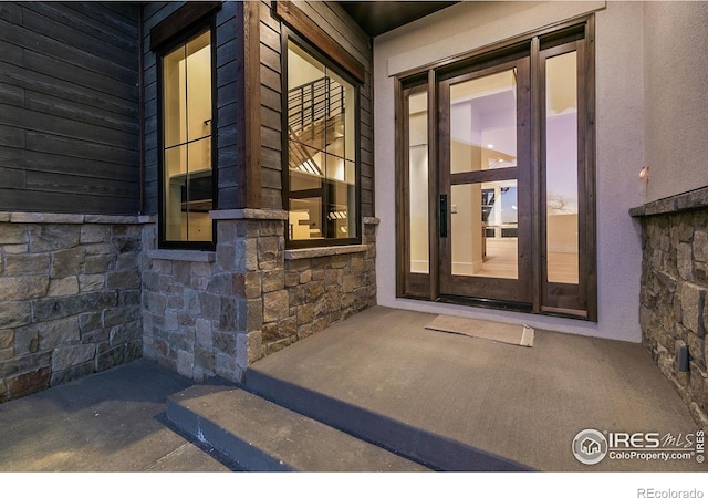 exterior entry at dusk with stone siding and stucco siding