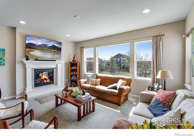 living room with baseboards, recessed lighting, a glass covered fireplace, and light colored carpet