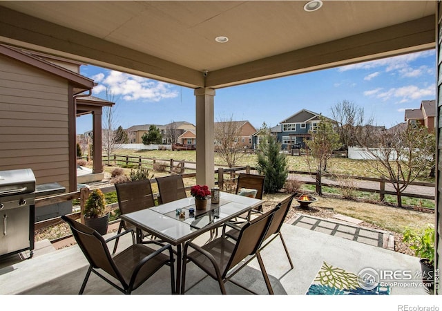 view of patio / terrace featuring outdoor dining area, fence, and a residential view