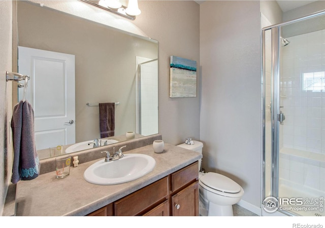 bathroom with toilet, a shower stall, and vanity