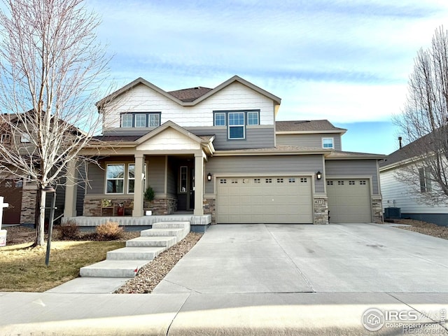 craftsman-style house with a garage, stone siding, covered porch, and driveway