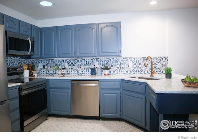 kitchen with light countertops, appliances with stainless steel finishes, a sink, and blue cabinets