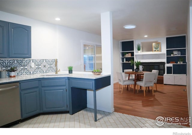 kitchen with light countertops, dishwasher, blue cabinetry, and a sink