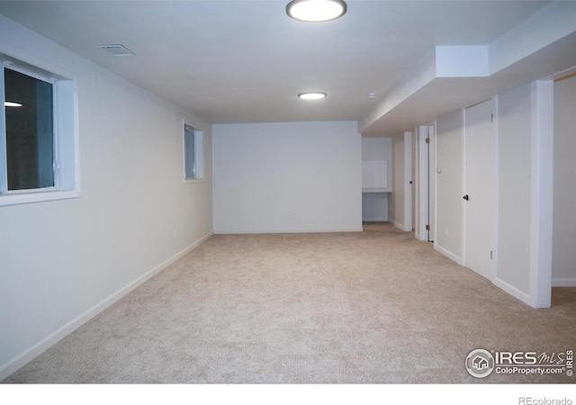 finished basement featuring baseboards, visible vents, and light colored carpet