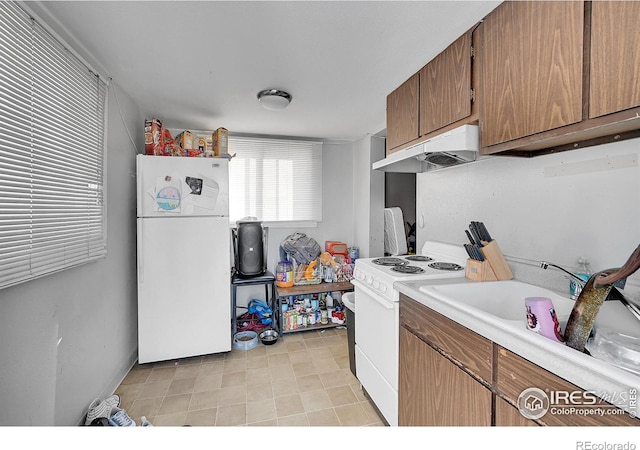 kitchen featuring light countertops, brown cabinetry, a sink, white appliances, and under cabinet range hood