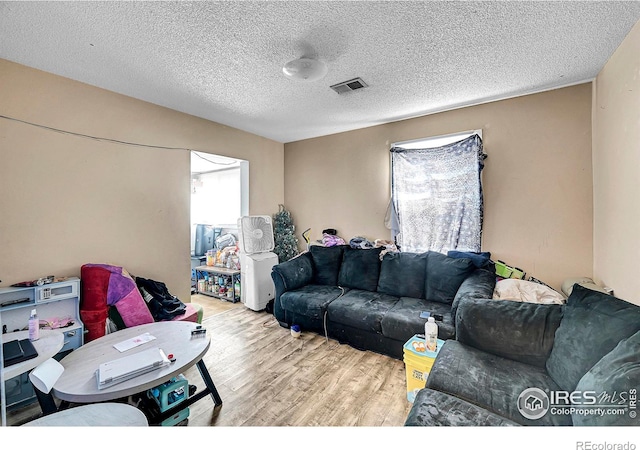 living room featuring a textured ceiling, visible vents, and wood finished floors