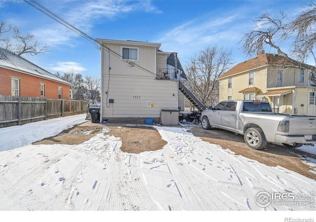 snow covered property with stairs, fence, and a residential view