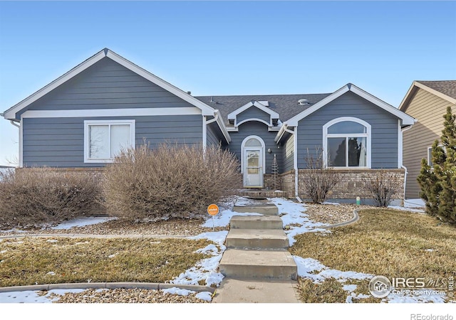 view of front of home with roof with shingles and a yard