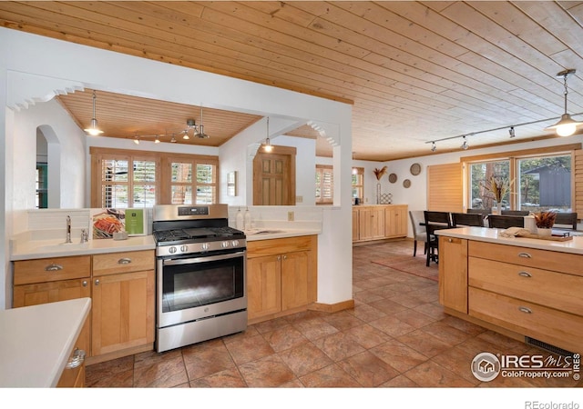 kitchen featuring wood ceiling, stainless steel range with gas stovetop, light countertops, pendant lighting, and a wealth of natural light