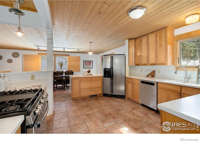 kitchen with stainless steel appliances, light countertops, a sink, and decorative light fixtures