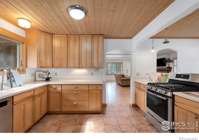 kitchen featuring decorative backsplash, appliances with stainless steel finishes, hanging light fixtures, light countertops, and a sink