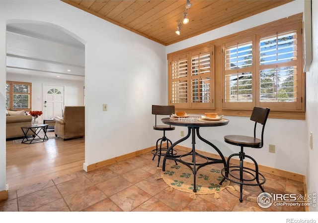 dining space featuring arched walkways, wooden ceiling, and baseboards