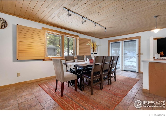 dining space with stone tile floors, ornamental molding, wood ceiling, track lighting, and baseboards