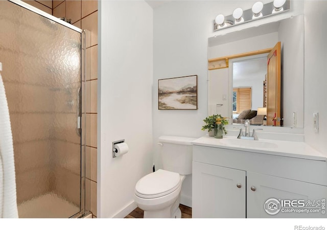 full bathroom featuring vanity, a shower stall, toilet, and baseboards