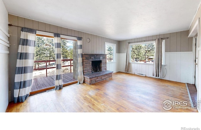 unfurnished living room featuring a stone fireplace, light wood finished floors, and visible vents