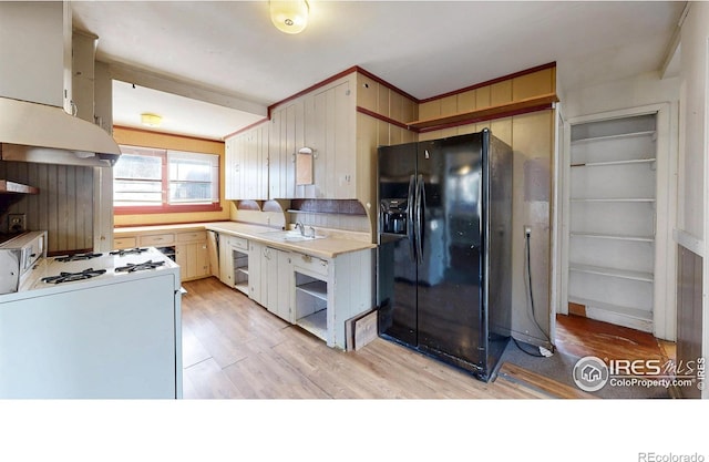 kitchen with a sink, black fridge with ice dispenser, light wood-style floors, light countertops, and white gas range