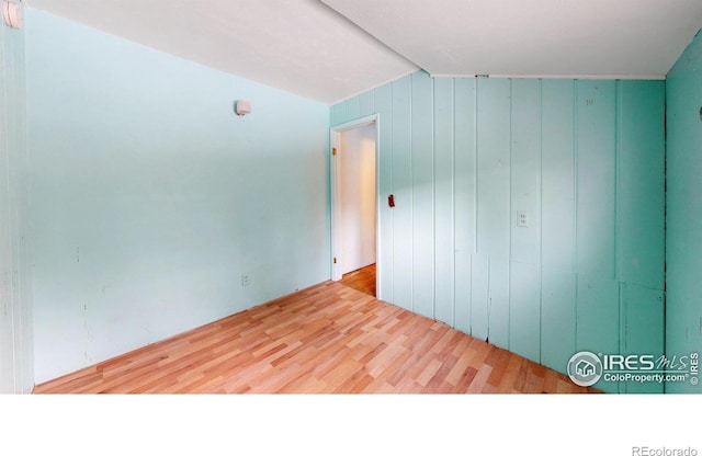 spare room featuring wooden walls and light wood finished floors