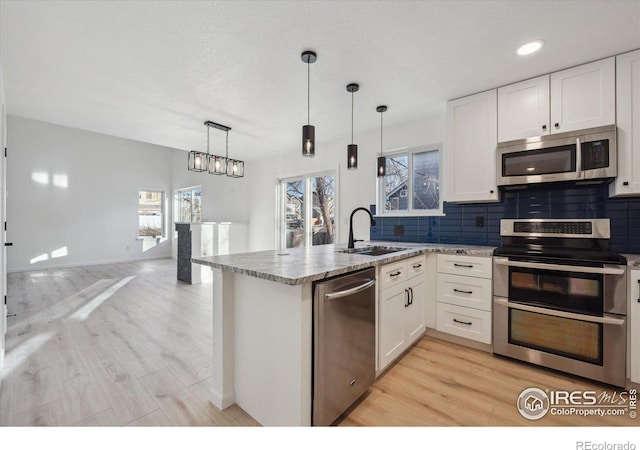 kitchen featuring pendant lighting, appliances with stainless steel finishes, a sink, and white cabinets